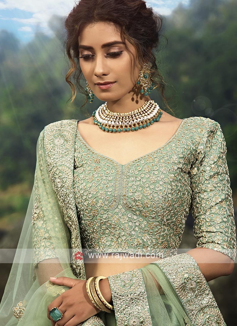 Photo of Bride posing in light pink lehenga and contrasting green jewellery